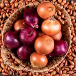 Onions in a basket with red onions top view on a shallots background